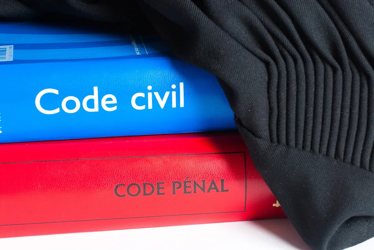 code civil et code pénal empilés avec une robe d'avocat, symbolisant le travail d'un avocat à Lyon